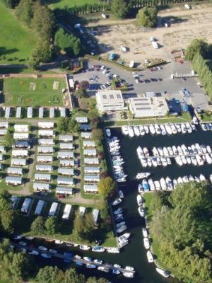Aerial view of a marina with boats, caravans, and a green landscape.