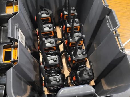 A grey container holding multiple two-way radios arranged neatly.